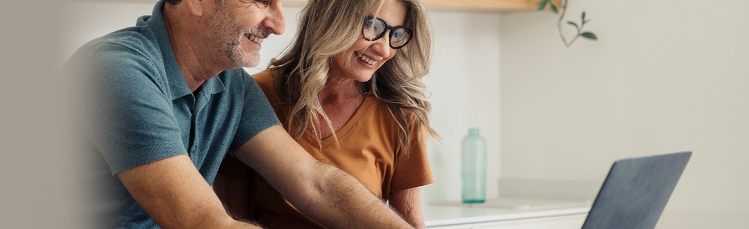 Couple Using LotVue Mortgage Calculator Online Smiling middle-aged couple using a laptop at home to explore the LotVue mortgage calculator tool